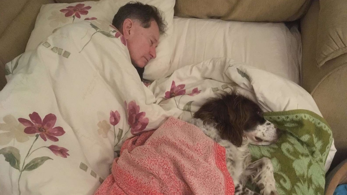 Un homme dort avec son chien âgé pour l'accompagner dans ses derniers jours